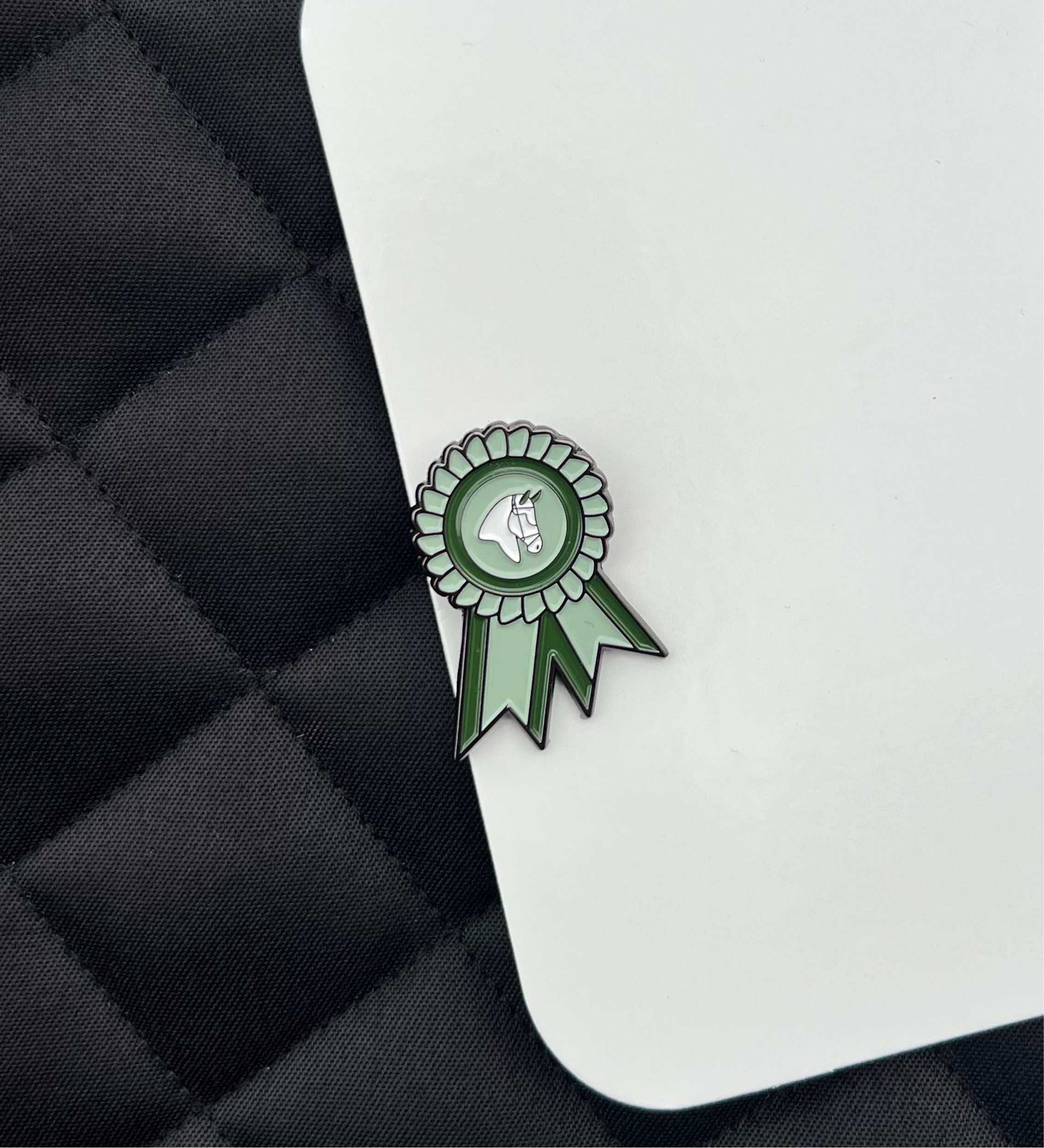 Green number pins with a horse icon on a black saddle pad.