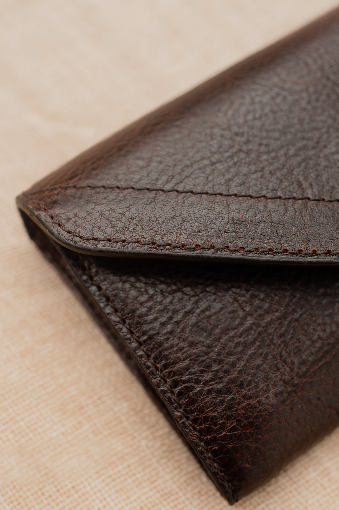 Detail of dark brown pebbled leather equestrian belt bag and fine stitching.
