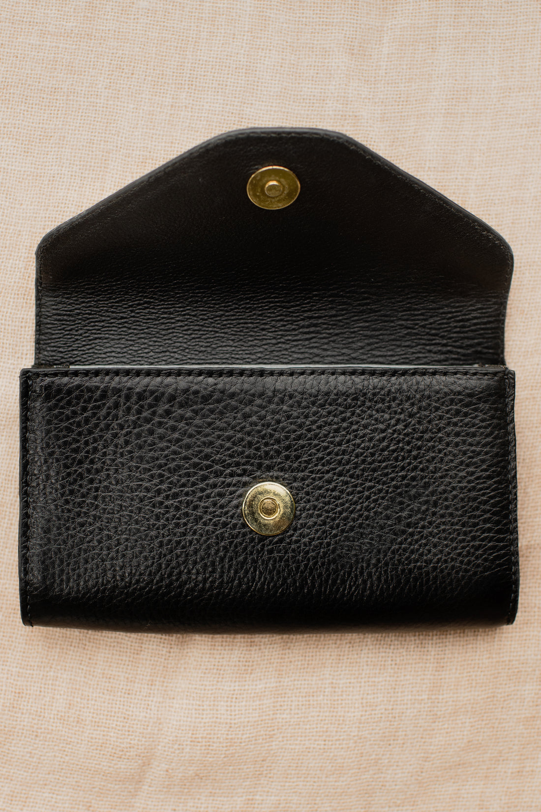 Black pebbled leather equestrian belt bag with envelope fold and brass snap hardware.