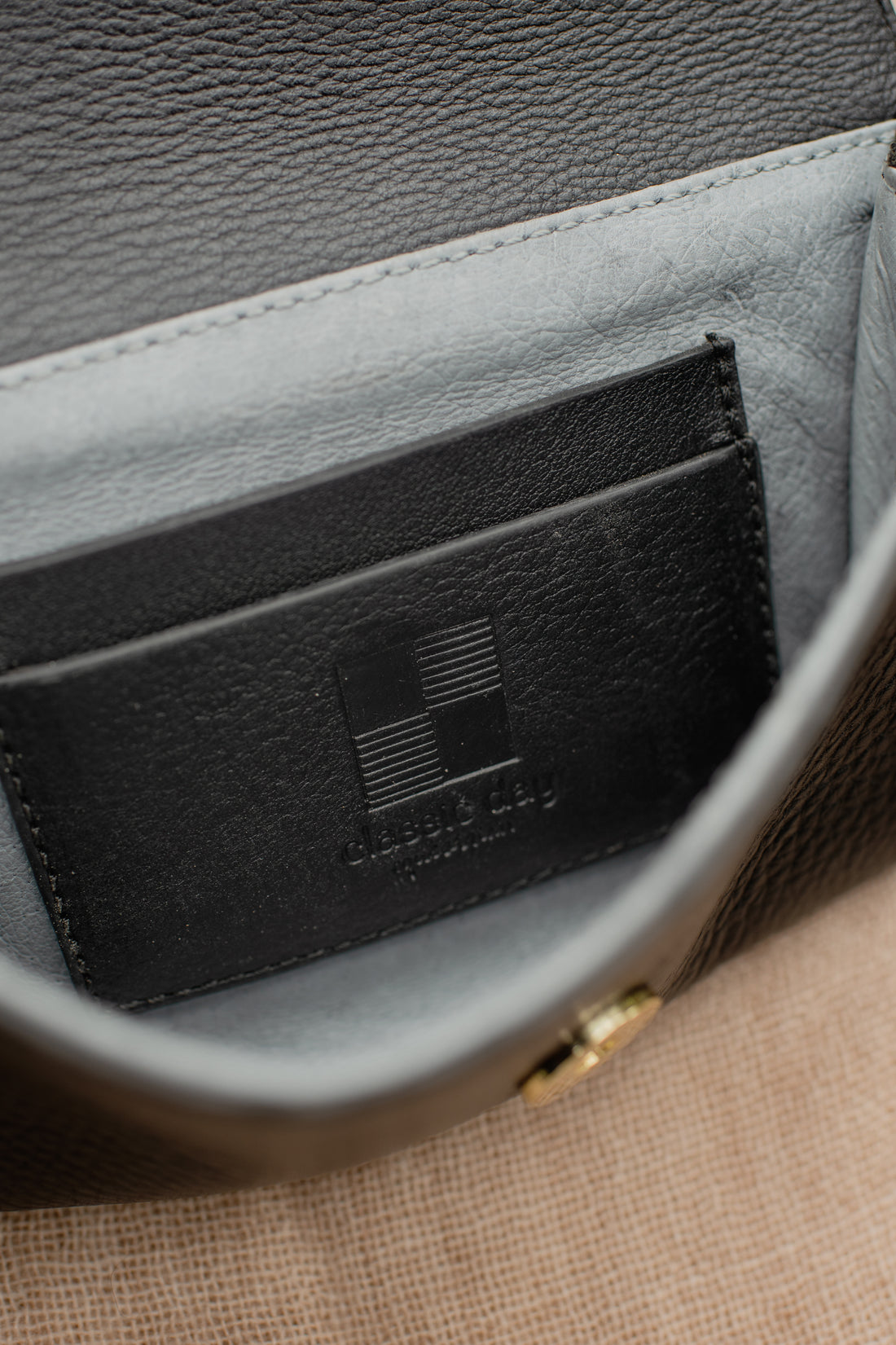 Close-up of the interior of a black leather wallet with embossed “Classic Day” logo on a stitched leather patch