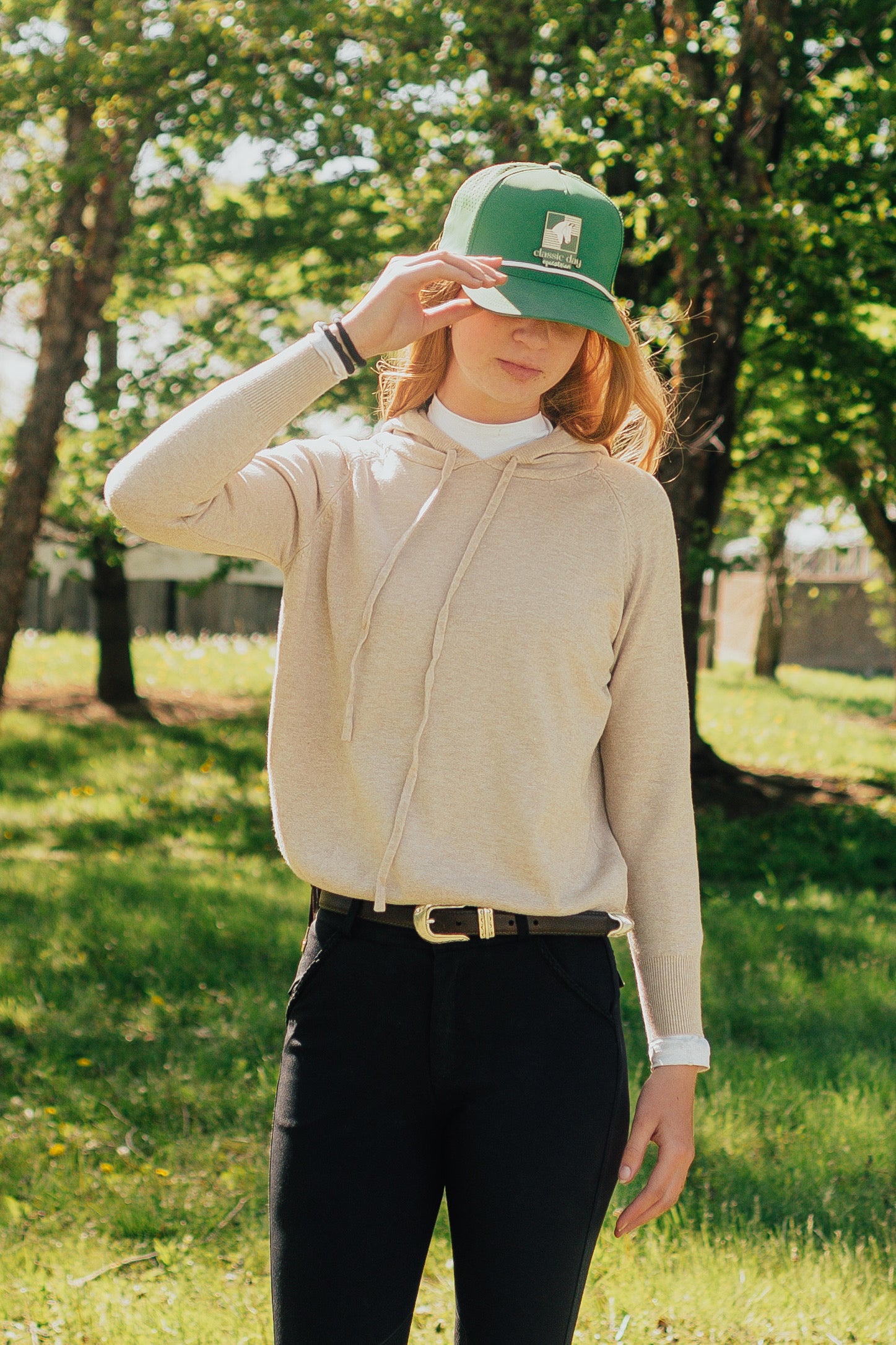 Person wearing a beige jacket and green cap in a park setting