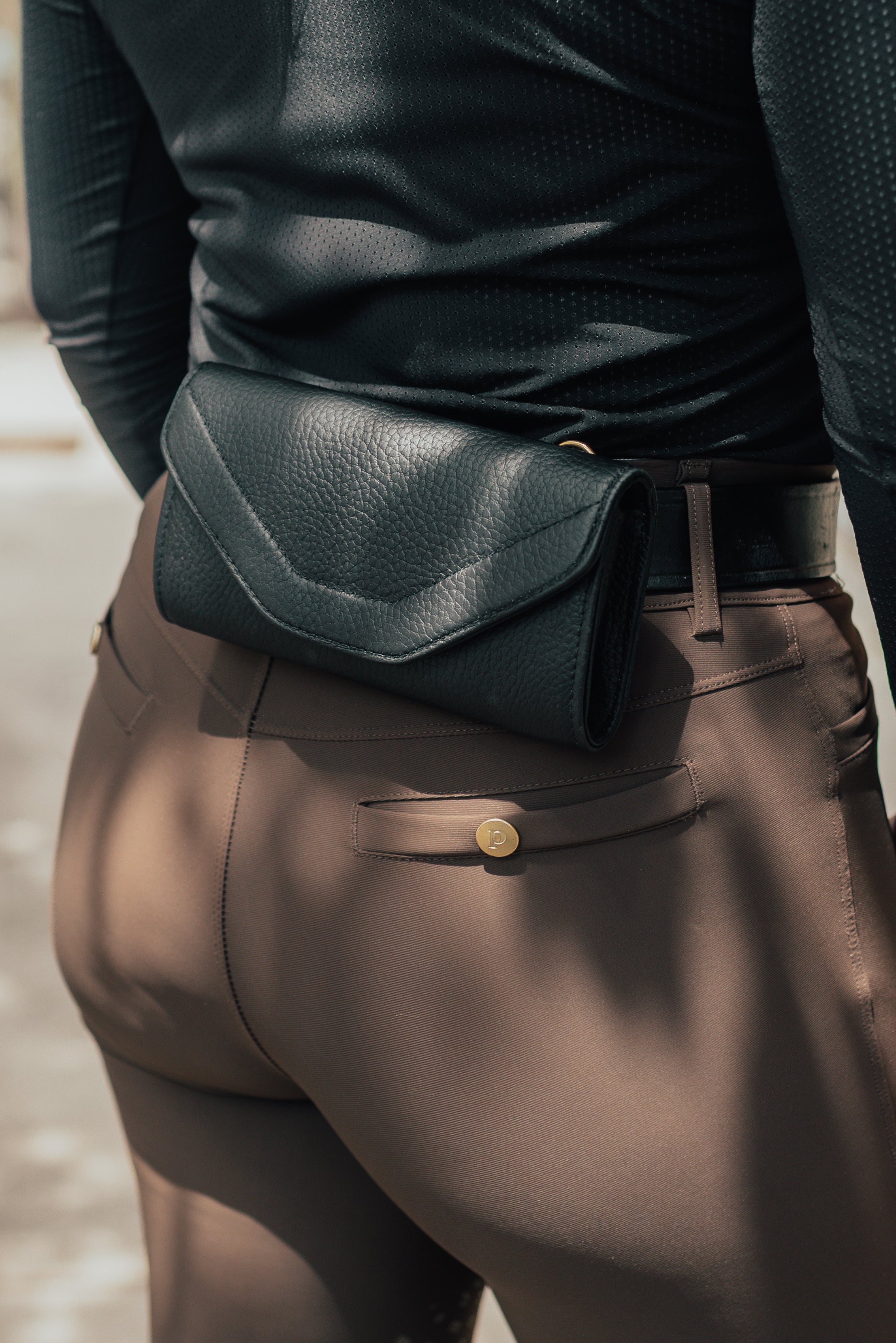 Person wearing a black belt bag with brown pants.